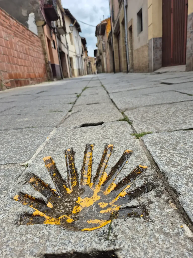 Yellow scallop-shell marker on the pavement on the Camino de Santiago