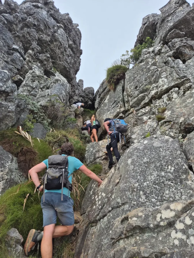 Hikers scrambling up rocky terrain