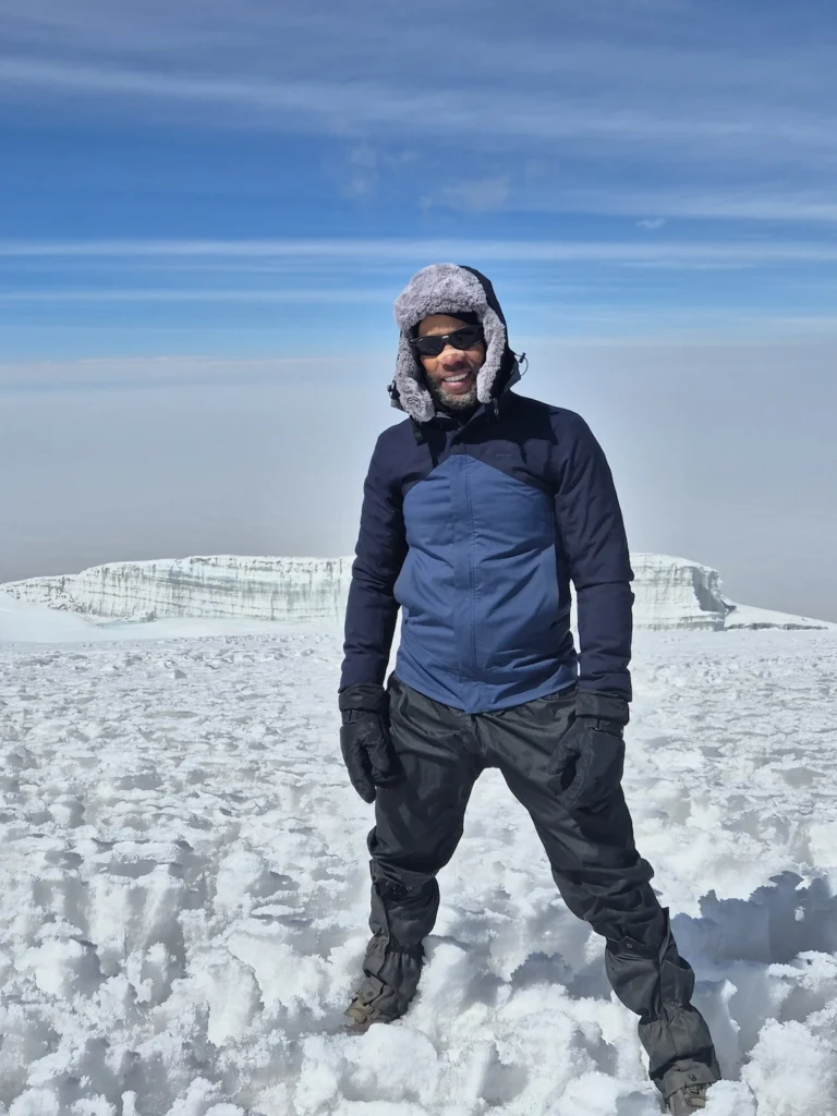 Simon standing in front of the glacier at the summit of Kilimanjaro