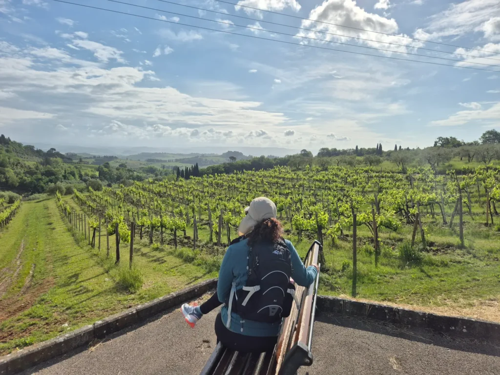 Eve sitting on a bench looking over vineyards and the Tuscan landscape 