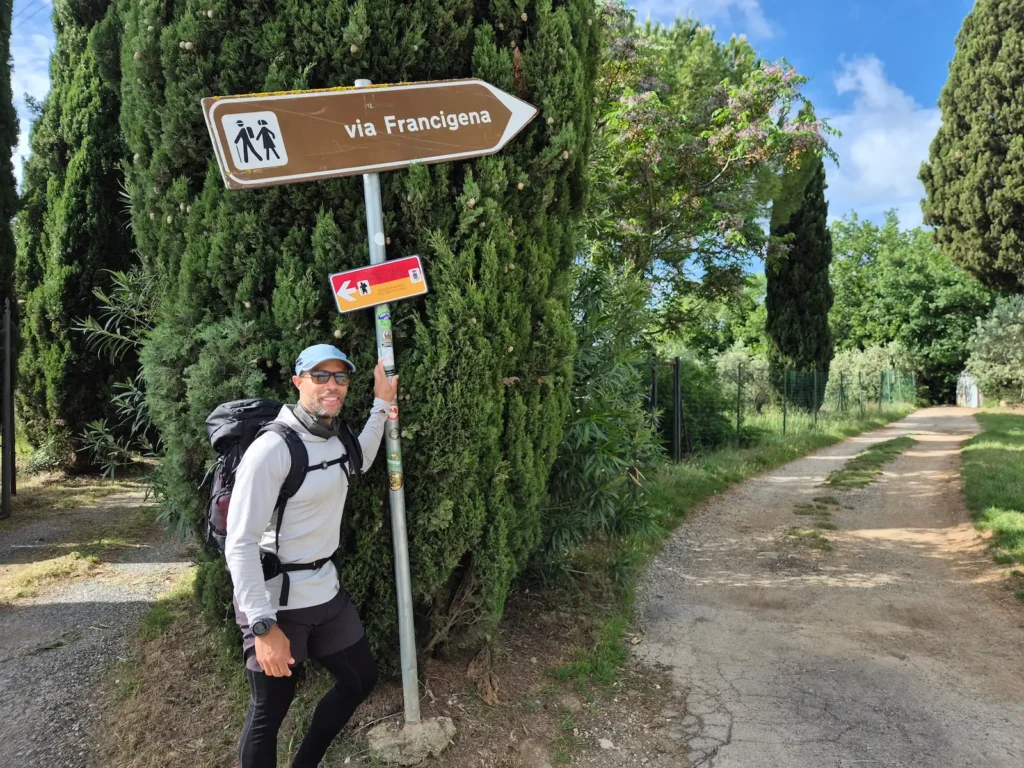 Simon standing in front of a Via Francigena sign in Tuscany