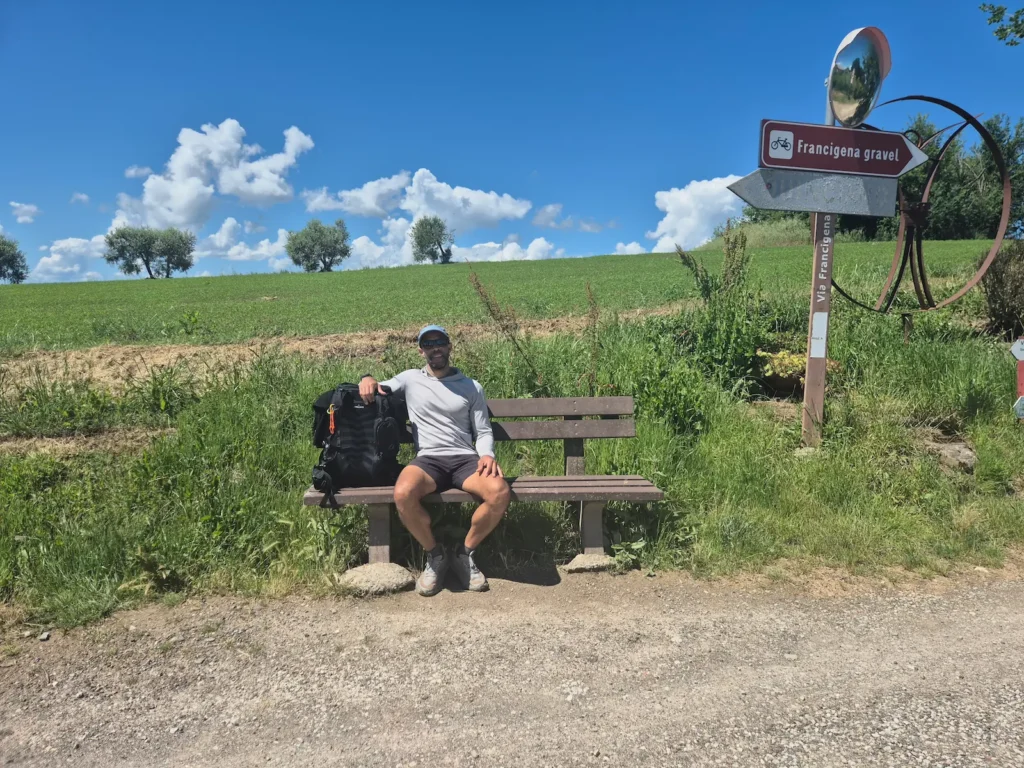 Simon sitting on a park bench in front of a wheat field