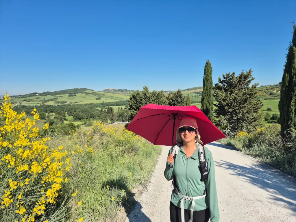 Eve under a red umbrella with the Tuscany's rolling hills behind her